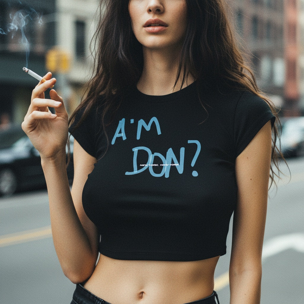 Woman wearing a black crop top with 'A'm Don?' text, holding a cigarette on a street.